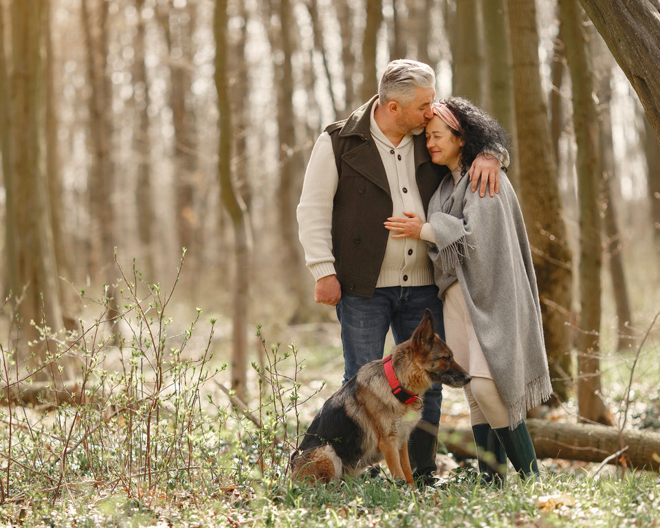Image of elderly couple and their dog walking in the woods