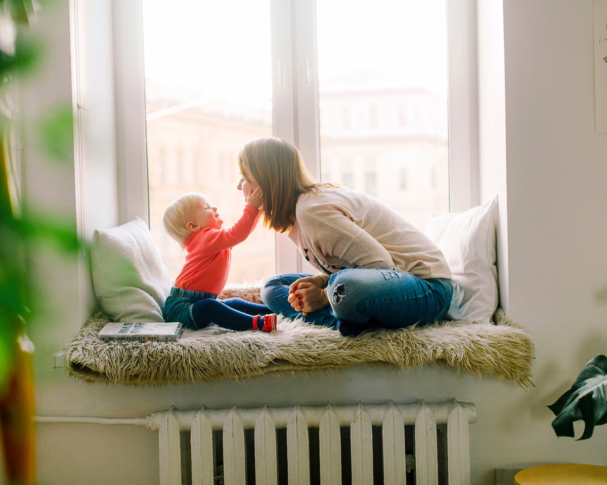 Image of woman playing with small child near window