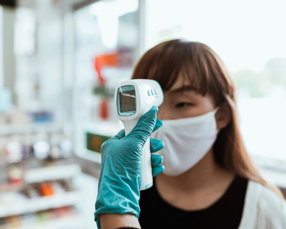 Image of woman wearing mask while getting her temperature checked at a retail store